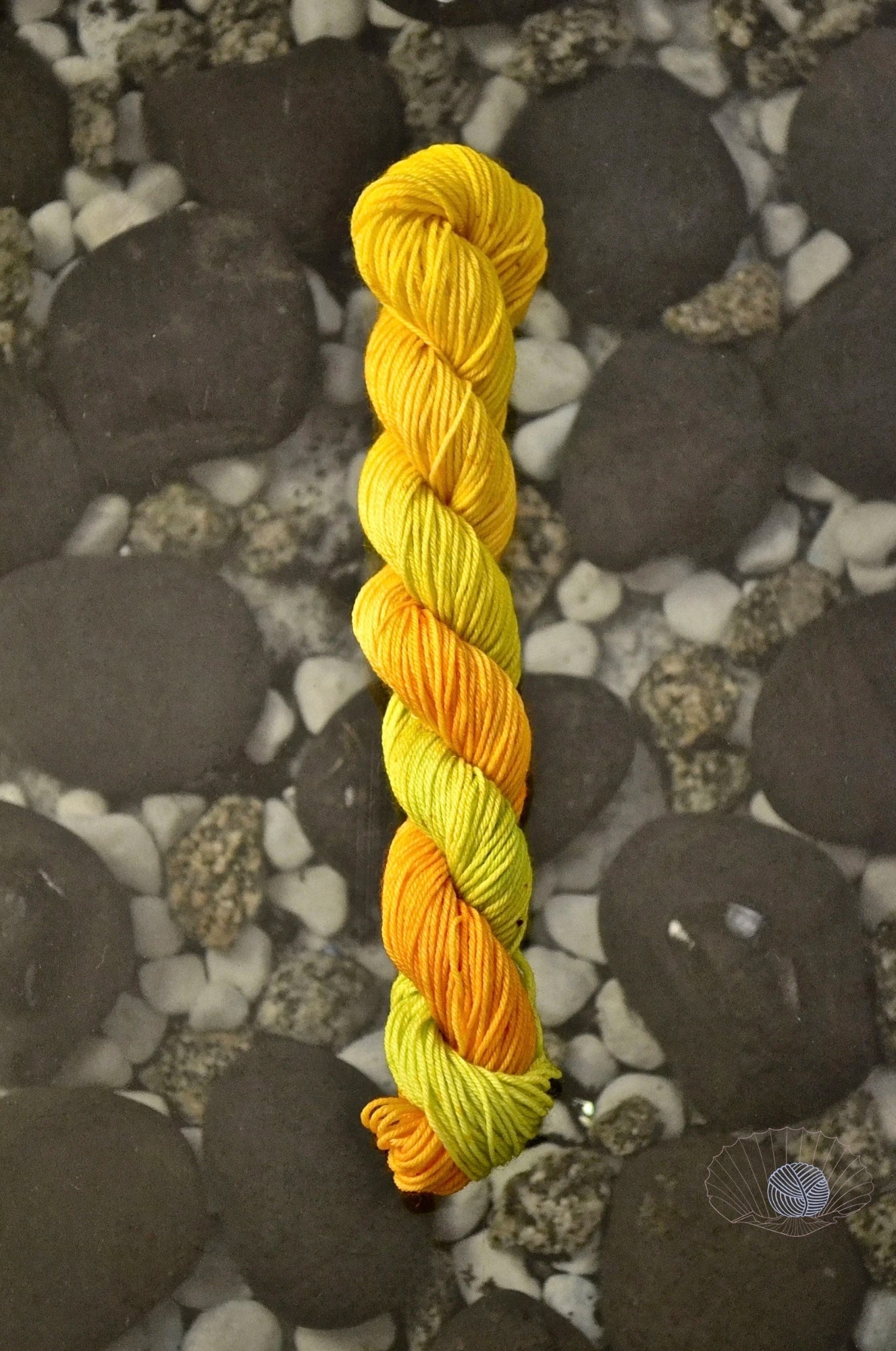 A gradient of orange to yellow to citron with speckling. Dyed on a mini skein of sock weight yarn.