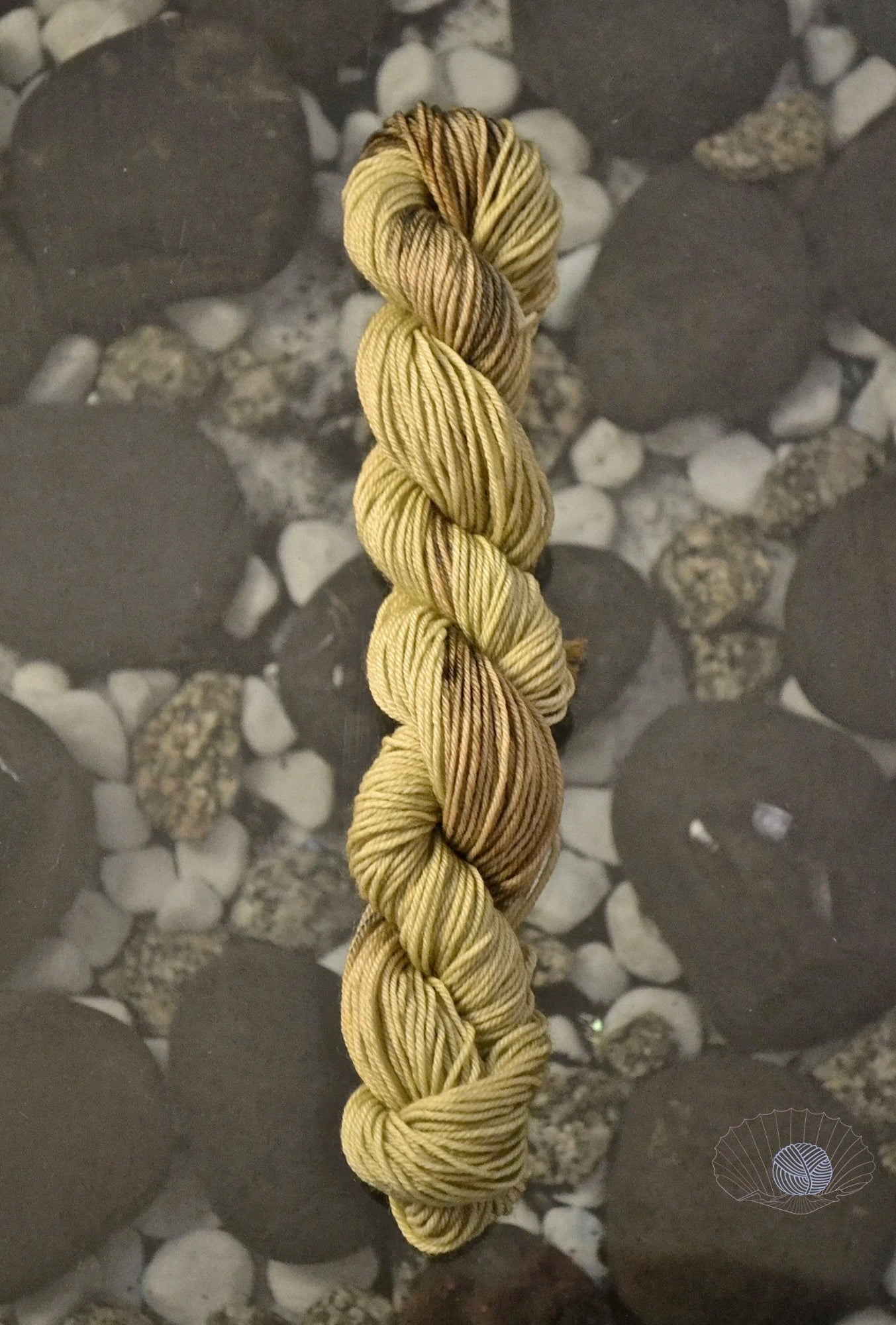 A self striping yarn with muddy pistachio and tan with brown spots. Dyed on a mini skein of sock weight yarn.
