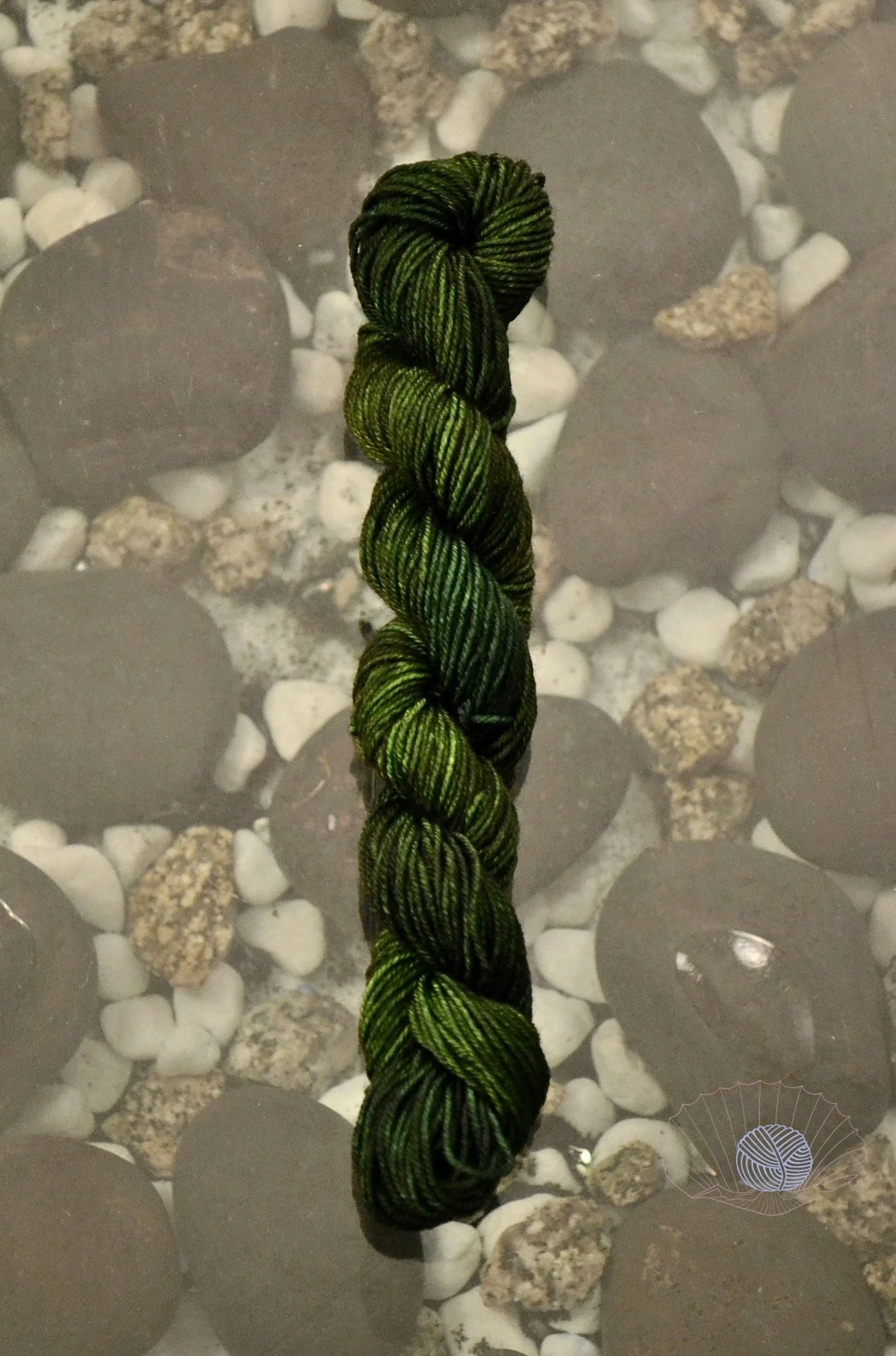 A tonal mix of muddy green, forest green, emerald, and pear. Dyed on a mini skein of sock weight yarn.