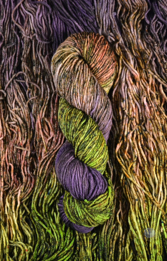 A gradient of purple to salmon to chartreuse, heavily speckled with brown. Dyed on worsted weight yarn.