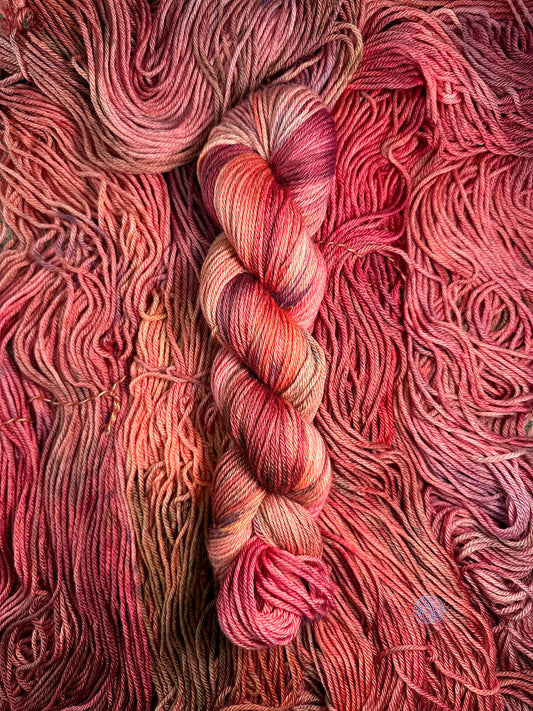 A variegated worsted weight yarn with shades of pink, salmon, beige, brown, burgundy, and purple